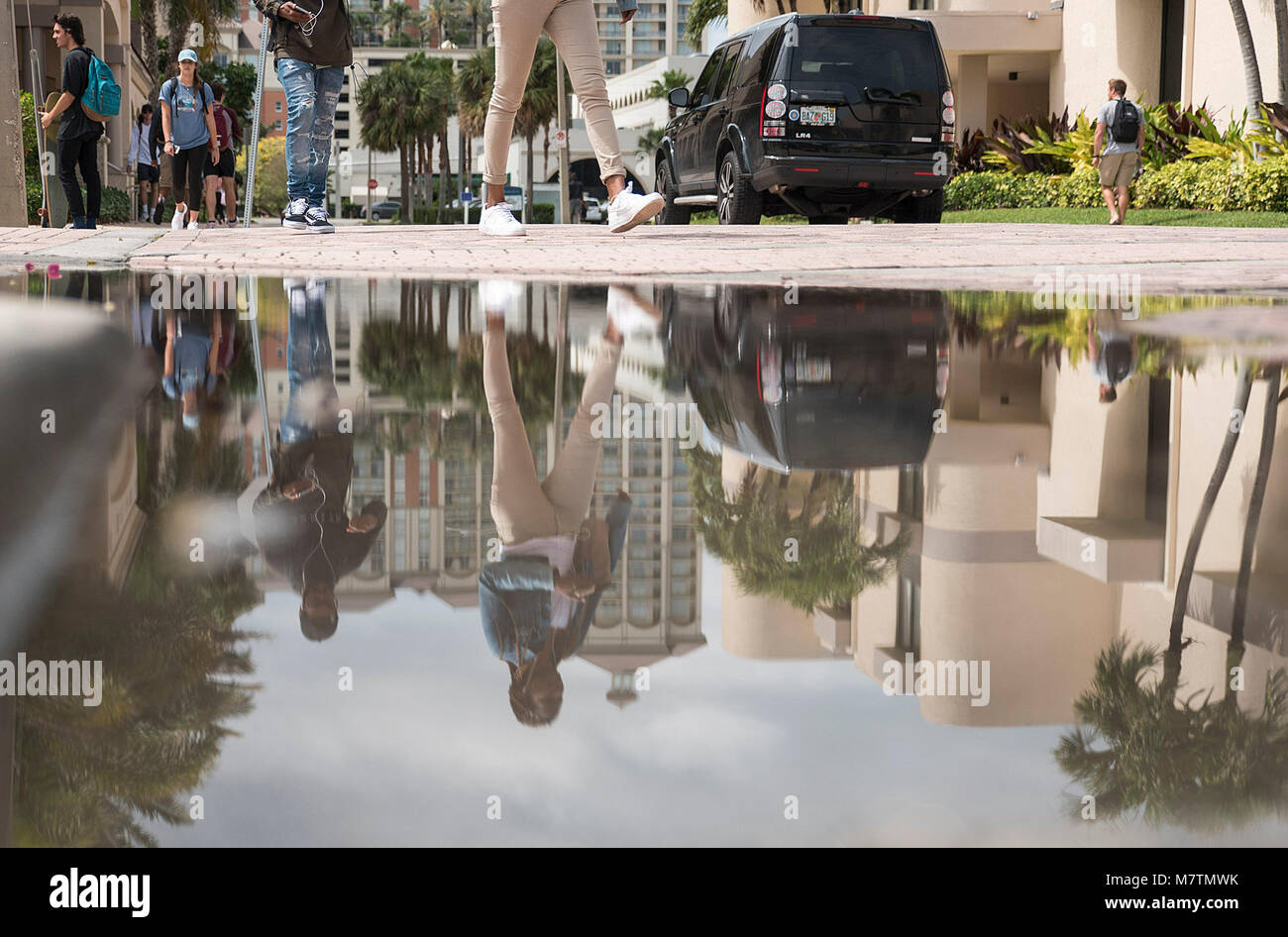 March 12, 2018 - West Palm Beach, Florida, U.S. - Passers-by on Vallowe Court on the Palm Beach Atlantic University campus walk past their reflections in a puddle after an afternoon shower in West Palm Beach, Fla., on Monday, March 12, 2018. (Credit Image: © Andres Leiva/The Palm Beach Post via ZUMA Wire) Stock Photo