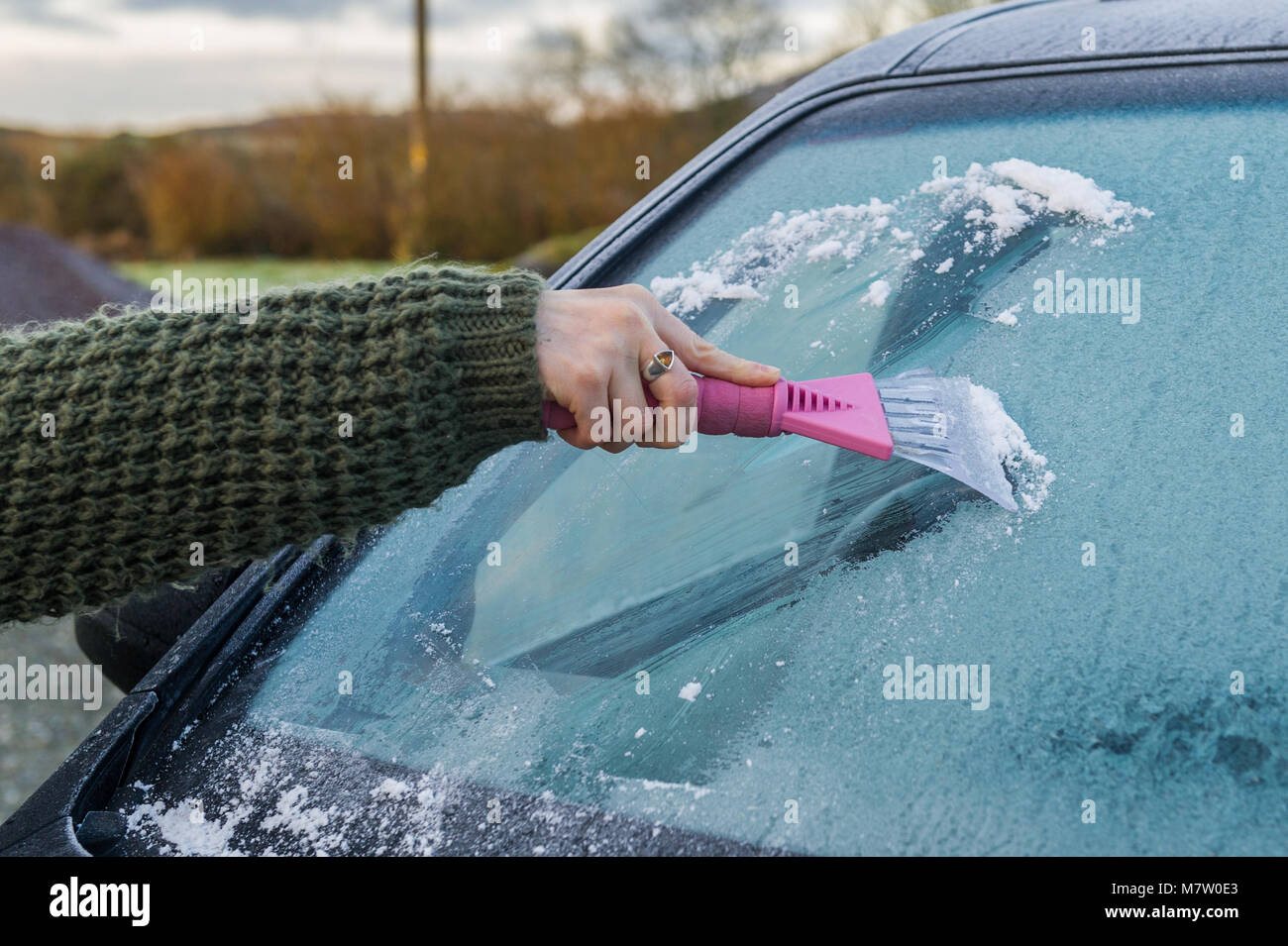 Ballydehob, Ireland. 13th Mar, 2018.  A woman defrosts  the windscreen of her car after a heavy night of frost. After a dry and bright morning, cloud will gradually increase bringing outbreaks of rain and drizzle this afternoon. Credit: AG News/Alamy Live News. Stock Photo