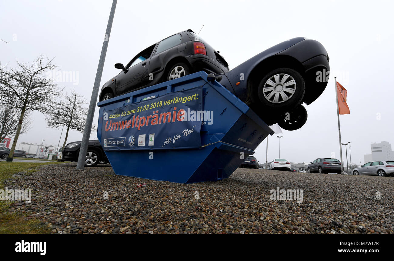 Schleswig, Germany. 13th March, 2018. Two cars stuck in a trash container. A Volkswagen dealership has installed the container in its premises as an eye-catcher for the topic of the environmental bonus for wrecking of old diesel cars. Photo: Carsten Rehder/dpa Credit: dpa picture alliance/Alamy Live News Stock Photo