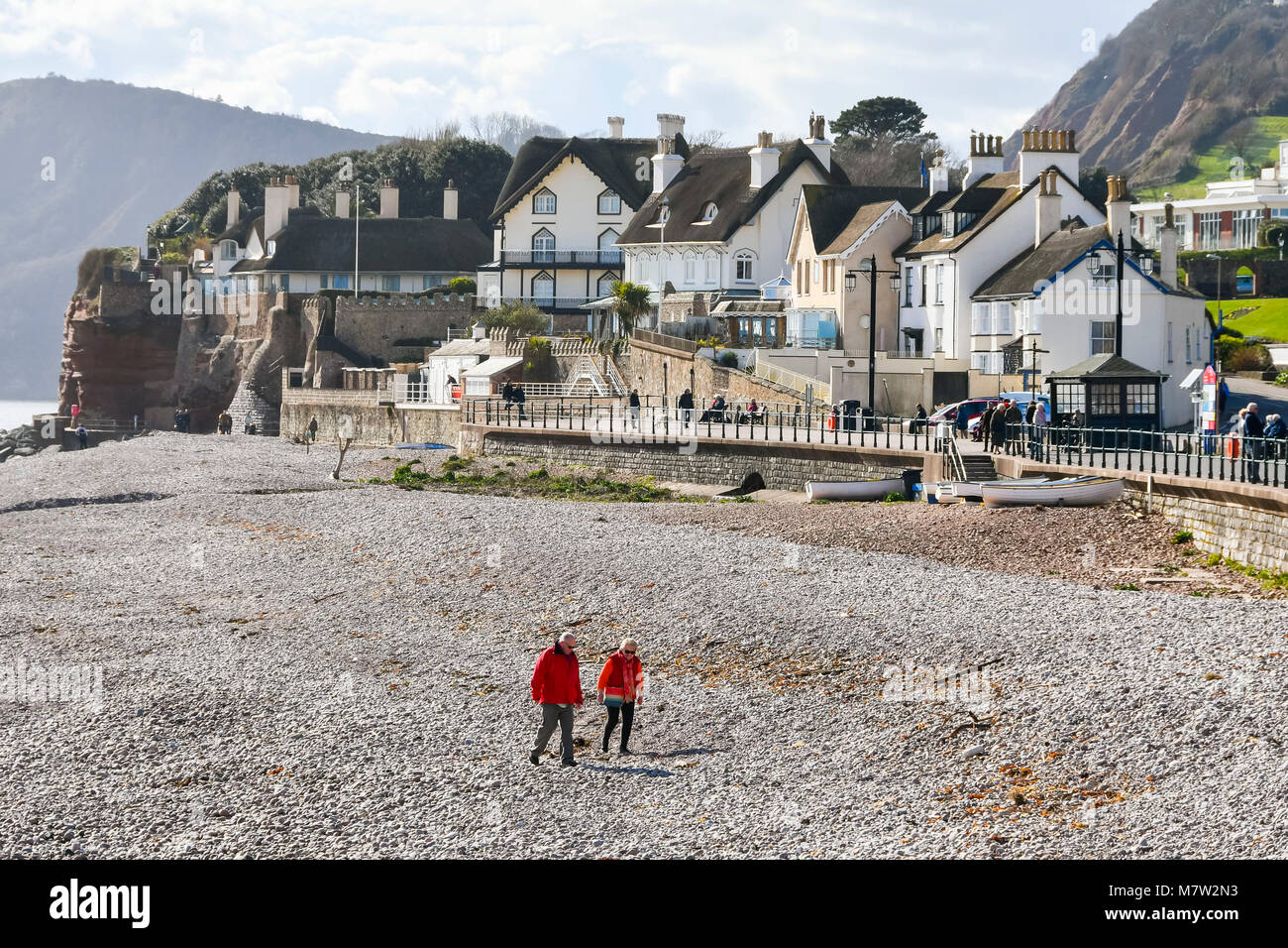 Sidmouth, Devon, UK.  13th March 2018.  UK Weather.  Visitors and residents enjoying a walk on the beach at the seaside town of Sidmouth in Devon on a warm sunny spring afternoon.  Picture Credit: Graham Hunt/Alamy Live News. Stock Photo