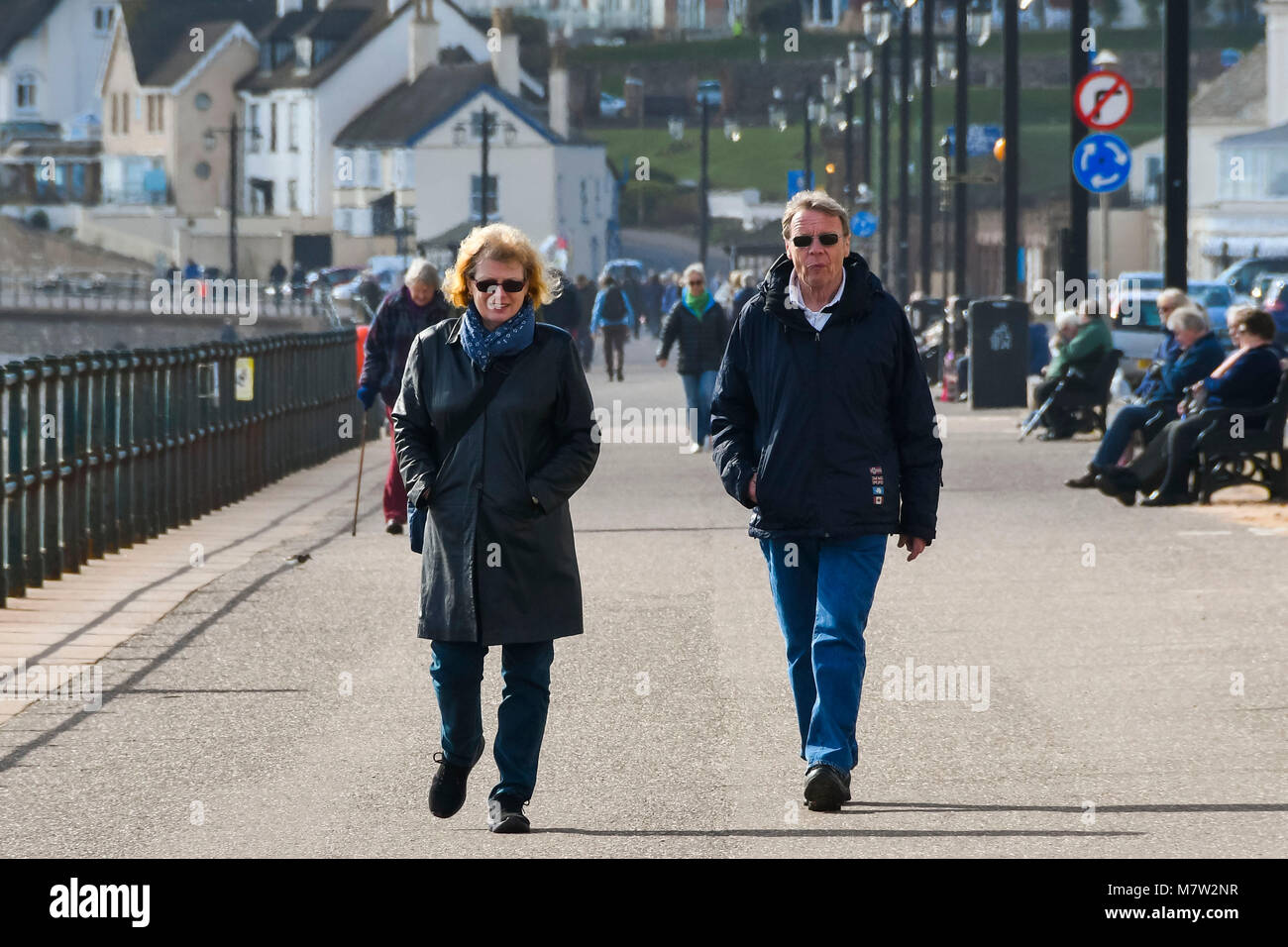 Sidmouth, Devon, UK.  13th March 2018.  UK Weather.  Visitors and residents enjoying a walk along the seafront at the seaside town of Sidmouth in Devon on a warm sunny spring afternoon.  Picture Credit: Graham Hunt/Alamy Live News. Stock Photo