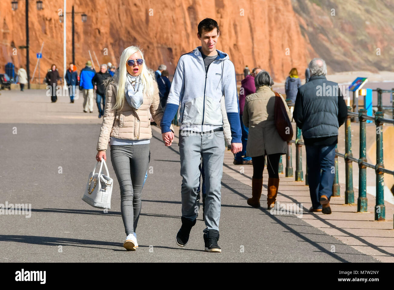 Sidmouth, Devon, UK.  13th March 2018.  UK Weather.  Visitors and residents enjoying a walk along the seafront at the seaside town of Sidmouth in Devon on a warm sunny spring afternoon.  Picture Credit: Graham Hunt/Alamy Live News. Stock Photo