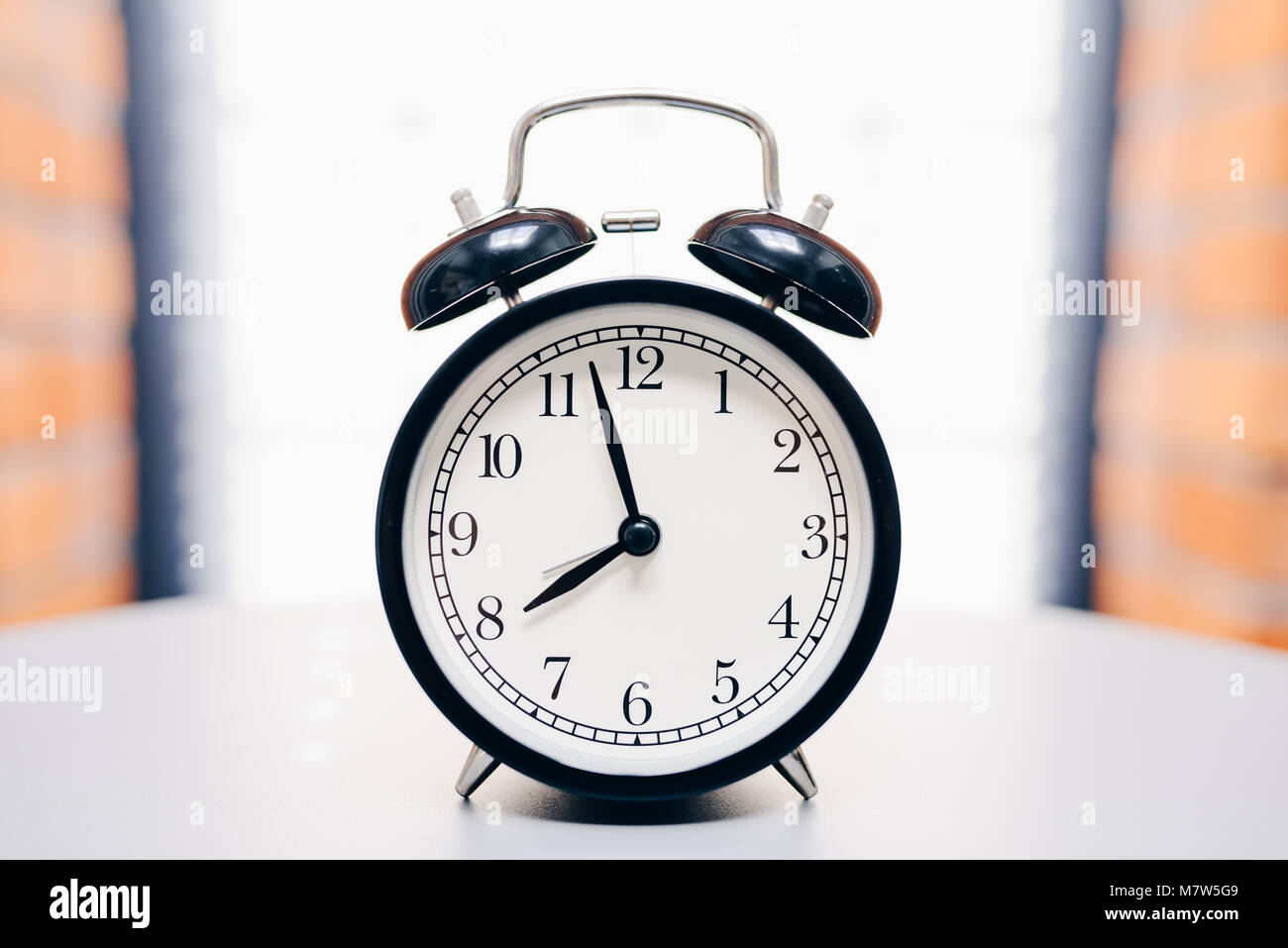 Retro alarm clock on table on white background Stock Photo - Alamy