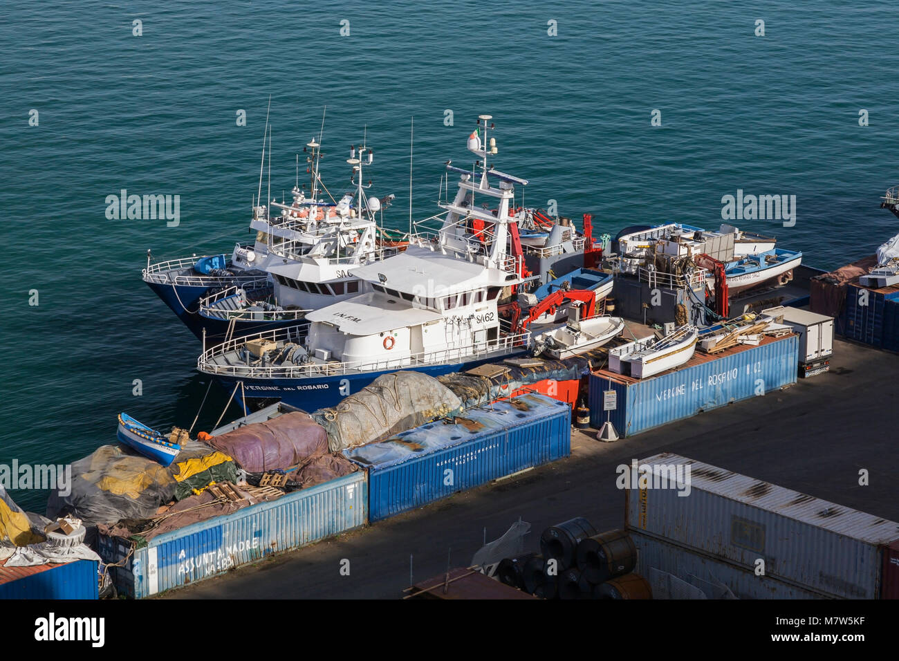 Blue shipping containers and fishing boats at dock in the port of Salerno, Italy, Europe. Stock Photo