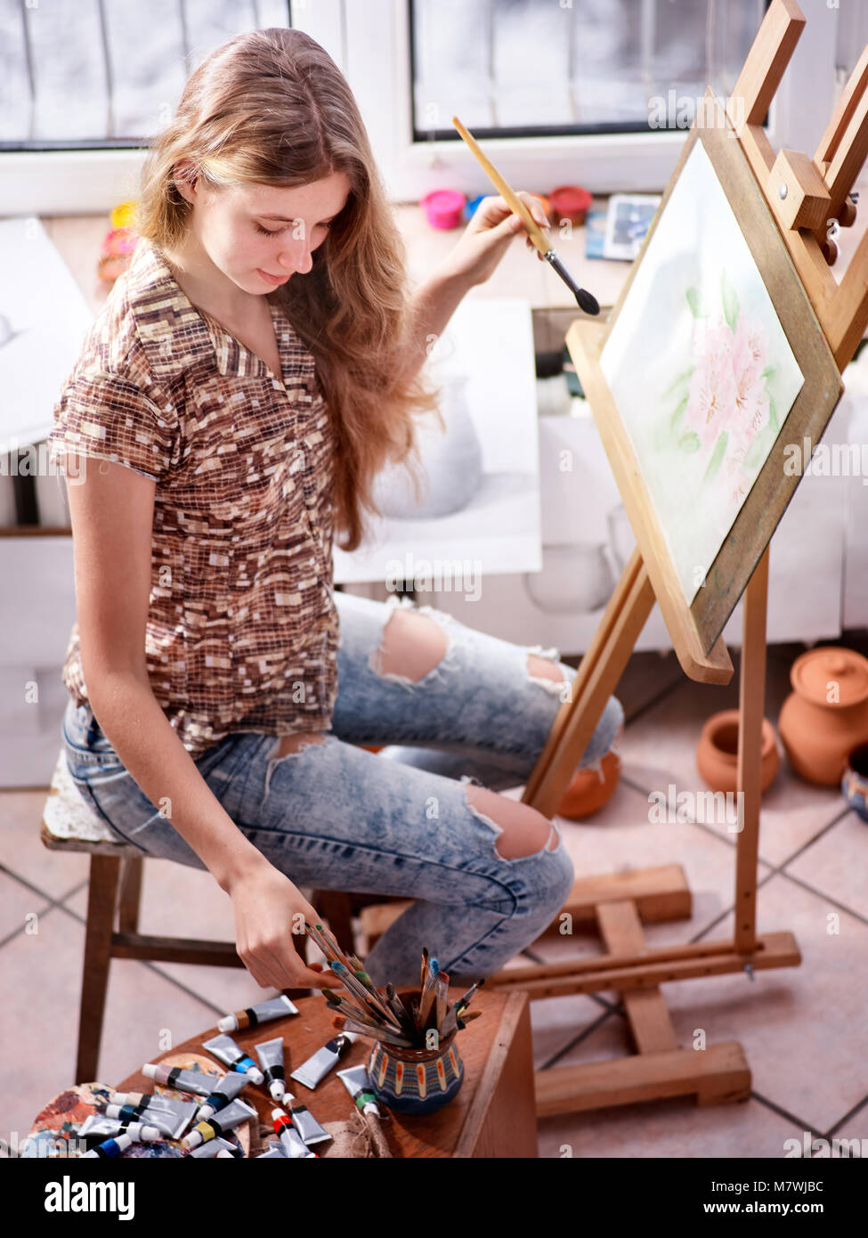 Artist painting on easel in studio. Girl paints with brush Stock Photo ...