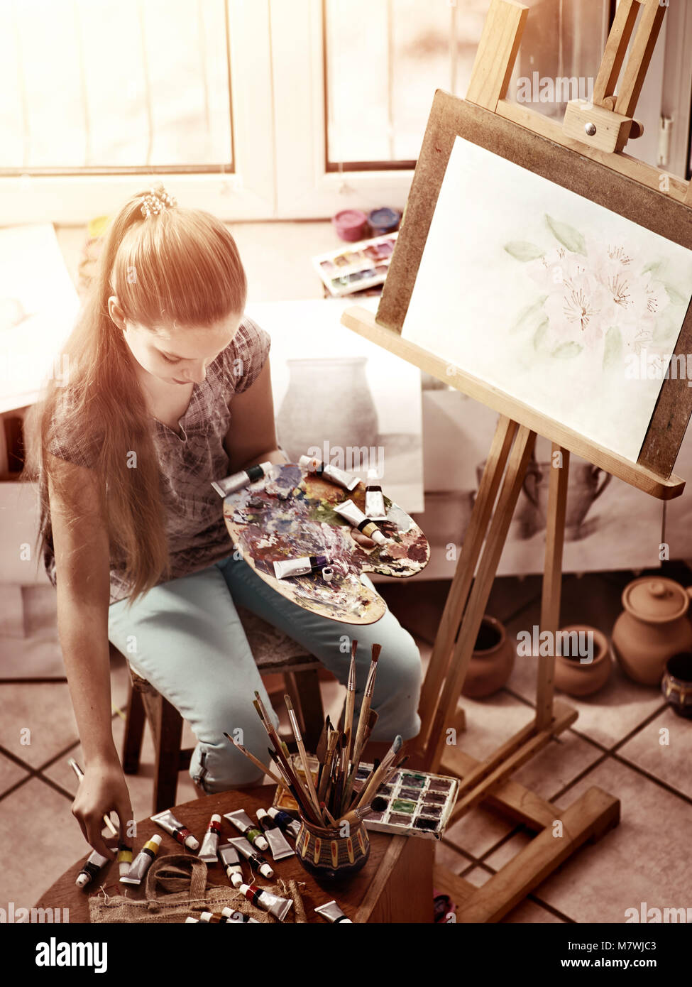 Artist painting on easel in studio. Girl paints with brush Stock Photo ...