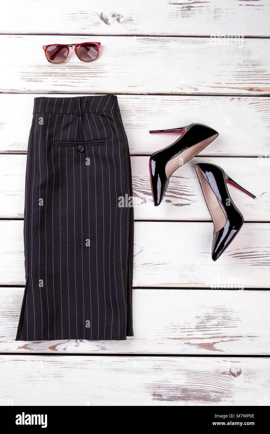 Black striped business skirt. Pair of shiny high heel shoes and spectacles. Stock Photo