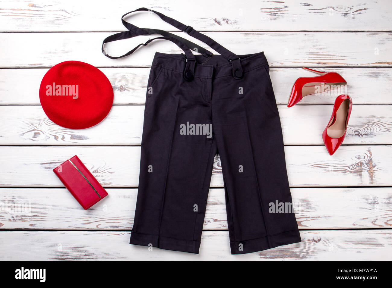 Black trousers with suspenders and red accessories. White wooden background top view. Stock Photo