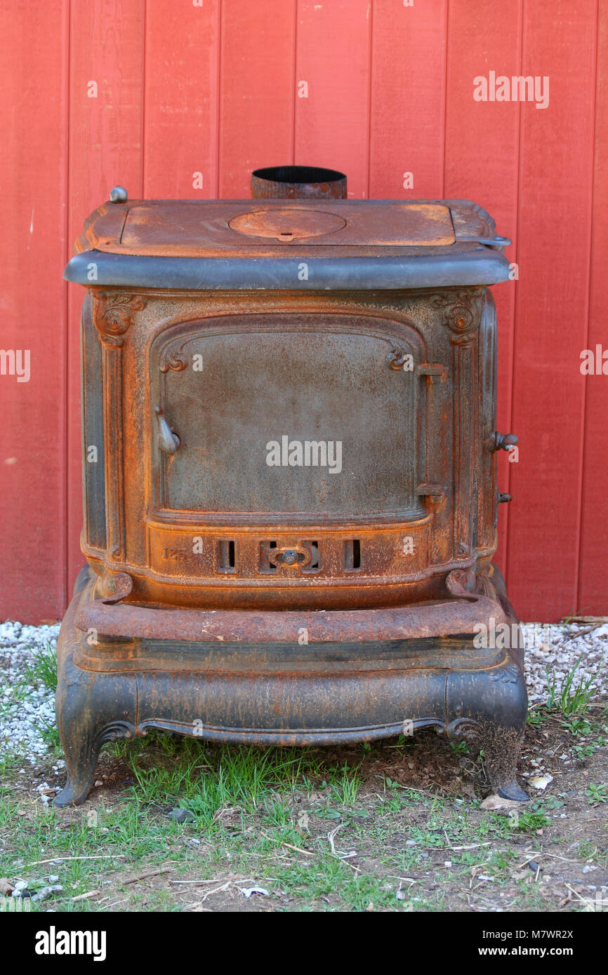 A Old rusty cast iron stove next to a barn Stock Photo