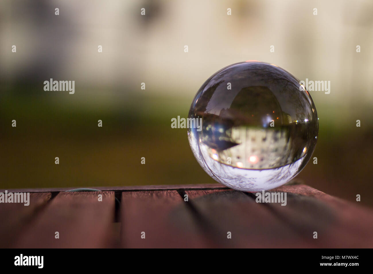 Refractions in a glass ball on a wooden table at dusk Stock Photo