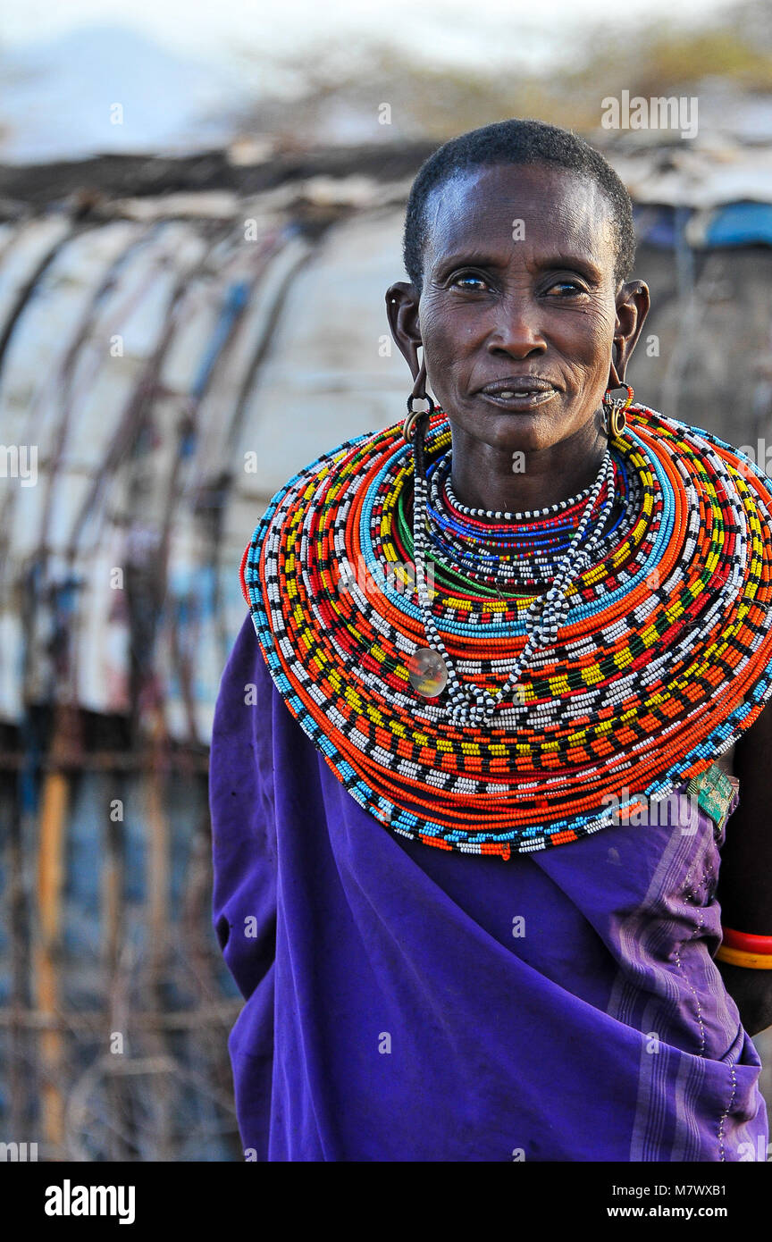 Portrait of an African woman in her tribal village. Wearing  traditional robes with elaborate beaded collar & earrings, denoting marital status. Stock Photo