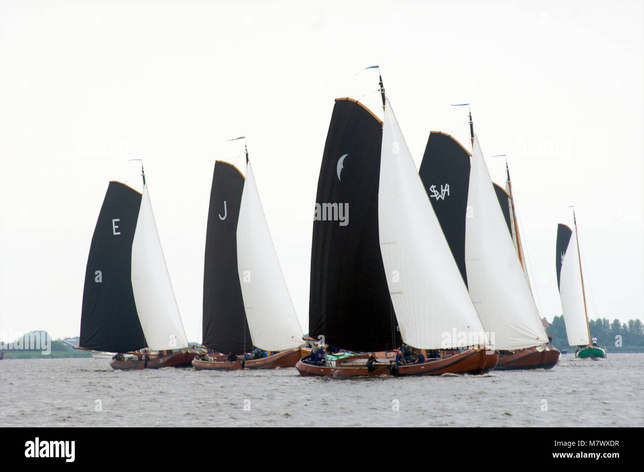 A traditional sailing race with classic Dutch wooden flat-bottemend boats on the lakes in Frisia, The Netherlands Stock Photo