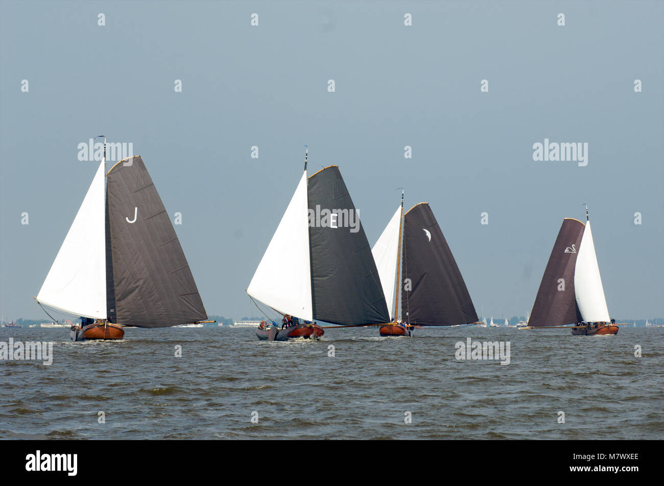 A traditional sailing race with classic Dutch wooden flat-bottemend boats on the lakes in Frisia, The Netherlands Stock Photo