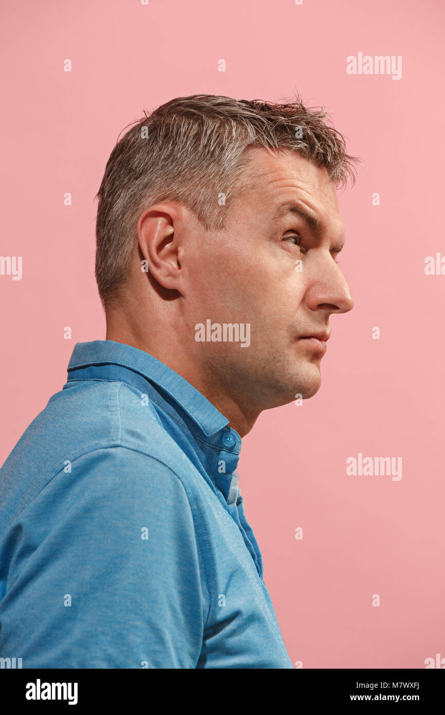 Suspiciont. Doubtful pensive man with thoughtful expression making choice against pink background Stock Photo