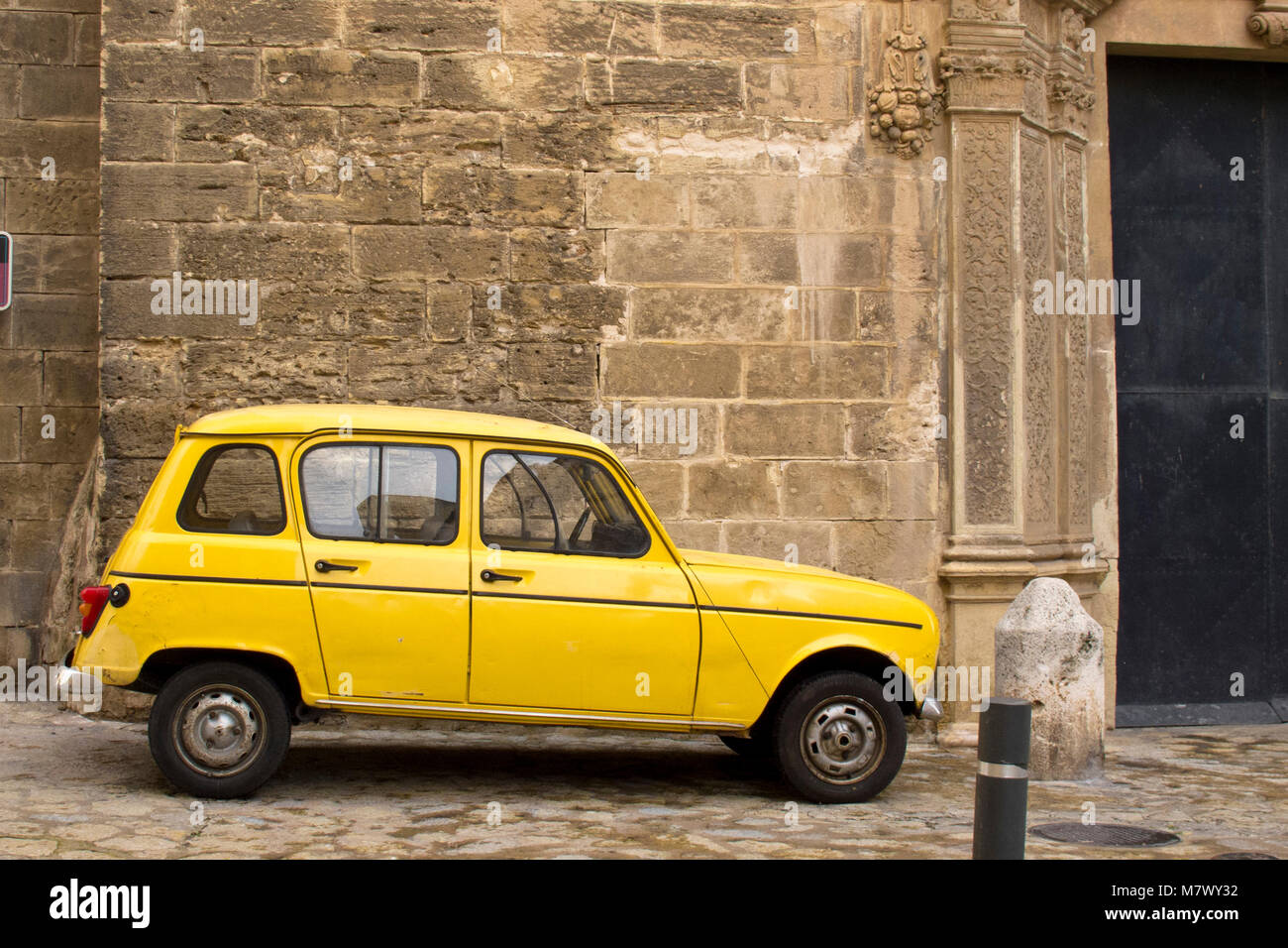 Old yellow car Renault 4 in bright yellow on the street in Palma Majorca Stock Photo