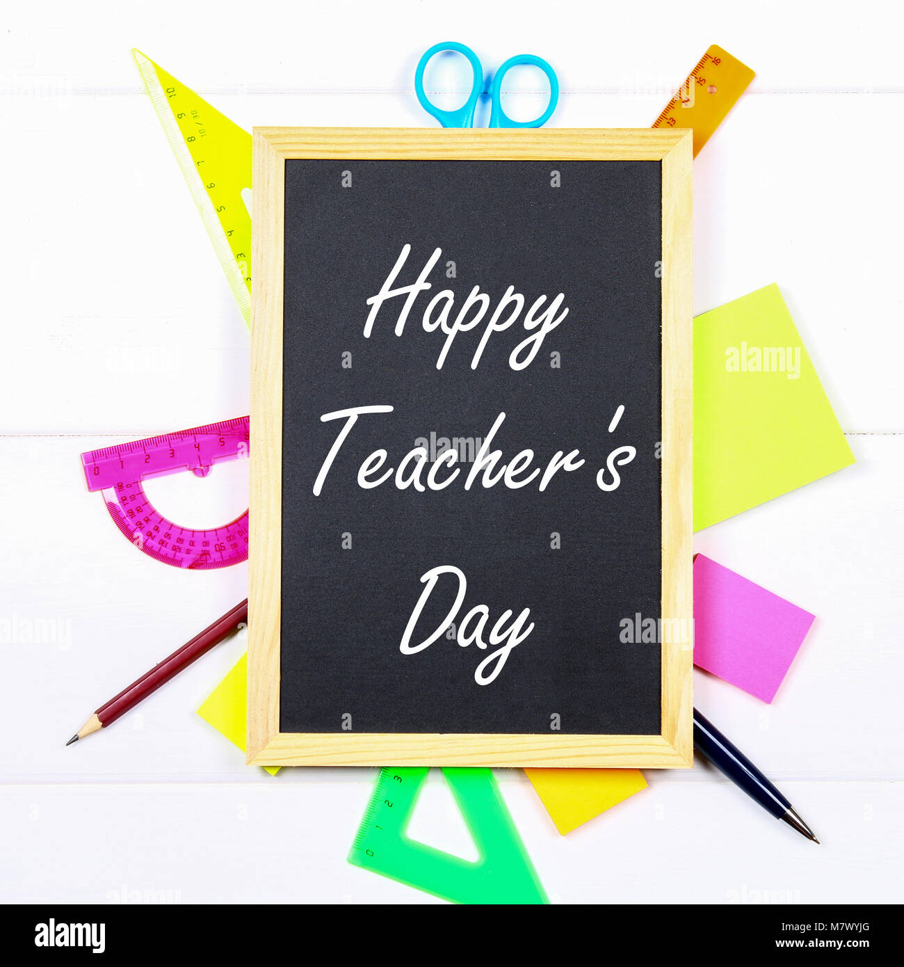 Text chalk on a chalkboard: Happy Teacher's Day. School supplies ...