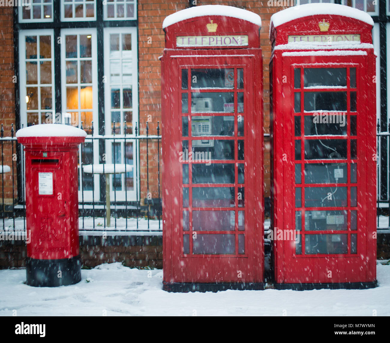 Typical British red pillar post box and telephone box covered in snow during blizzard Stock Photo