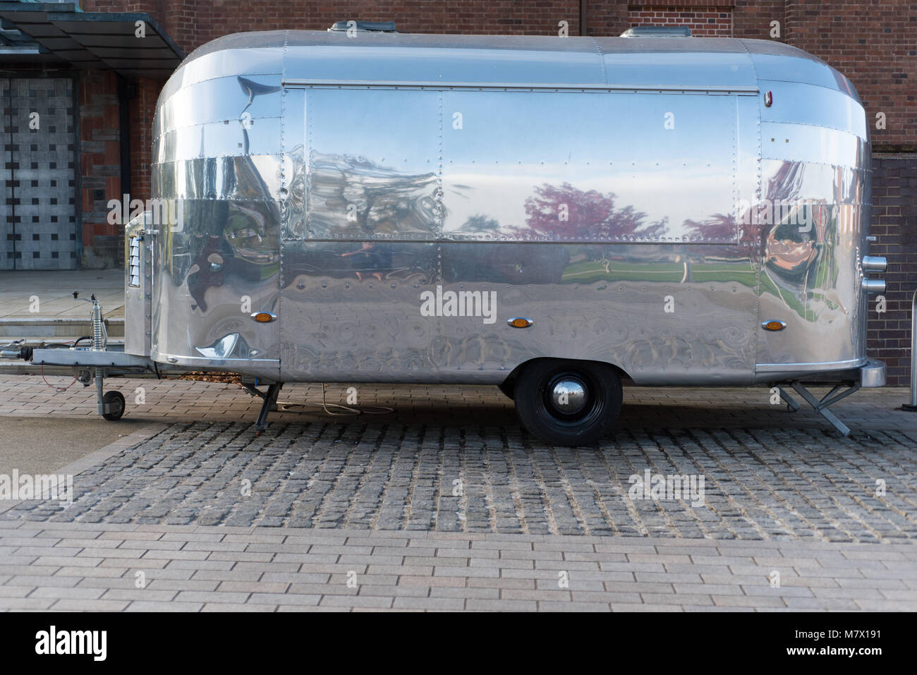 futuristic unmarked silver burger van with reflection of trees and space for caption Stock Photo