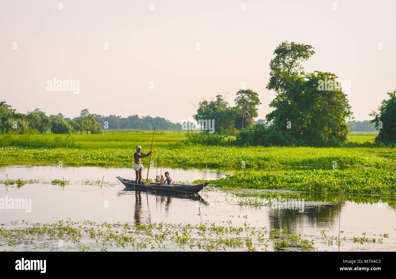 Father and son set nets and traps for shell fish at dawn in a lagoon in their tradition dugout wooden boat on August Stock Photo