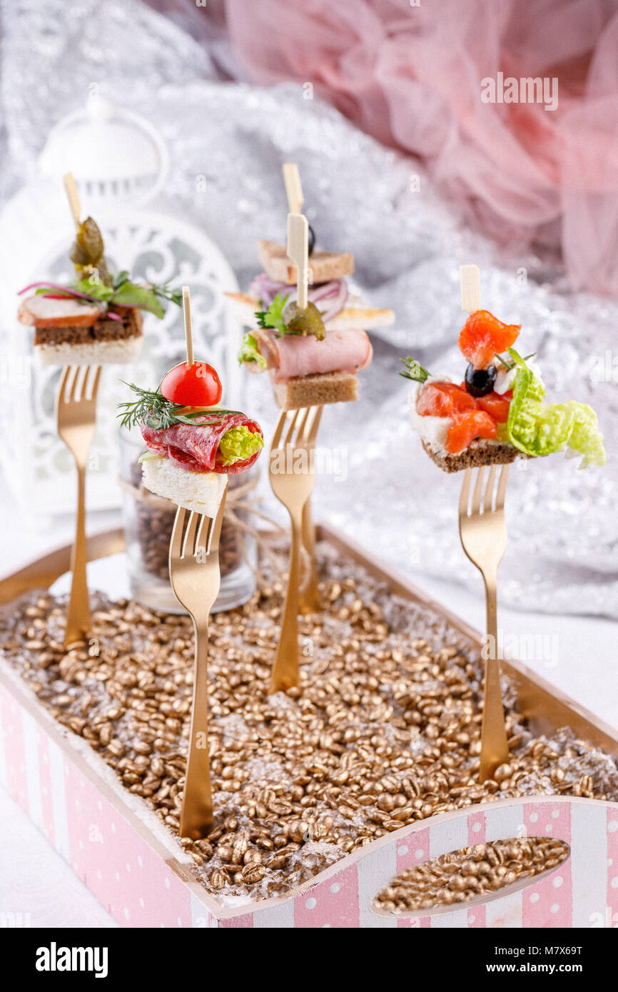 Original canapes on forks. Exquisite still life. Close-up. Stock Photo