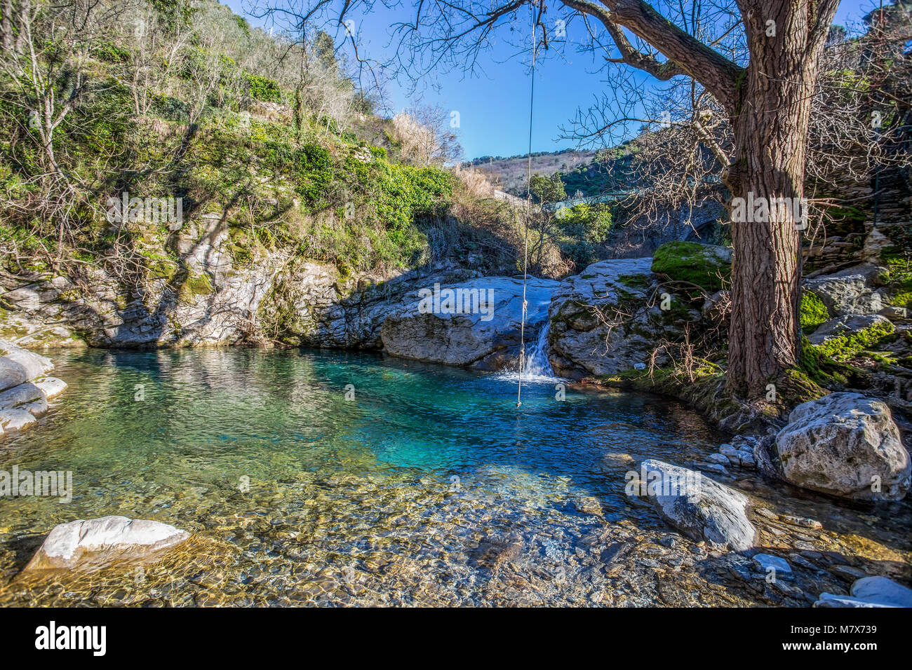 View of little waterfall on the river current in the sunlight. Pond with green and clear water. Stock Photo