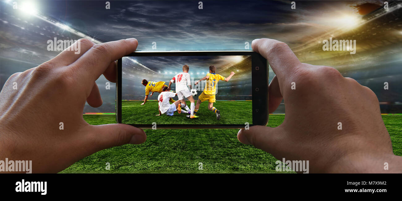 Stadium in the evening in full light before the match.   Football fan removes the football game on mobile phone 2018 Stock Photo