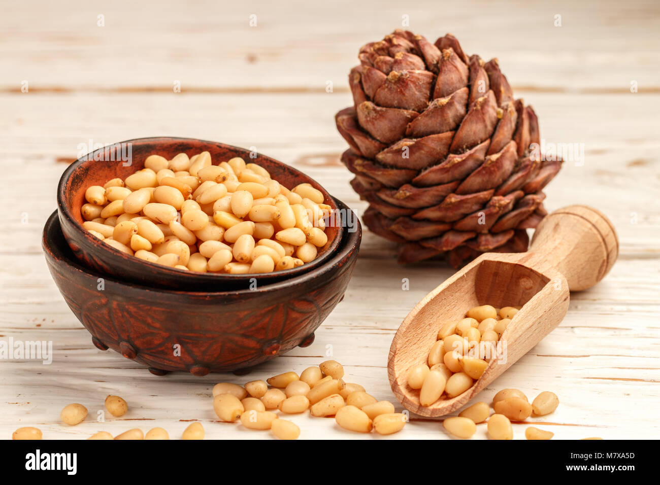 Cedar (Pine) nuts and cones on white wooden table. Selective focus