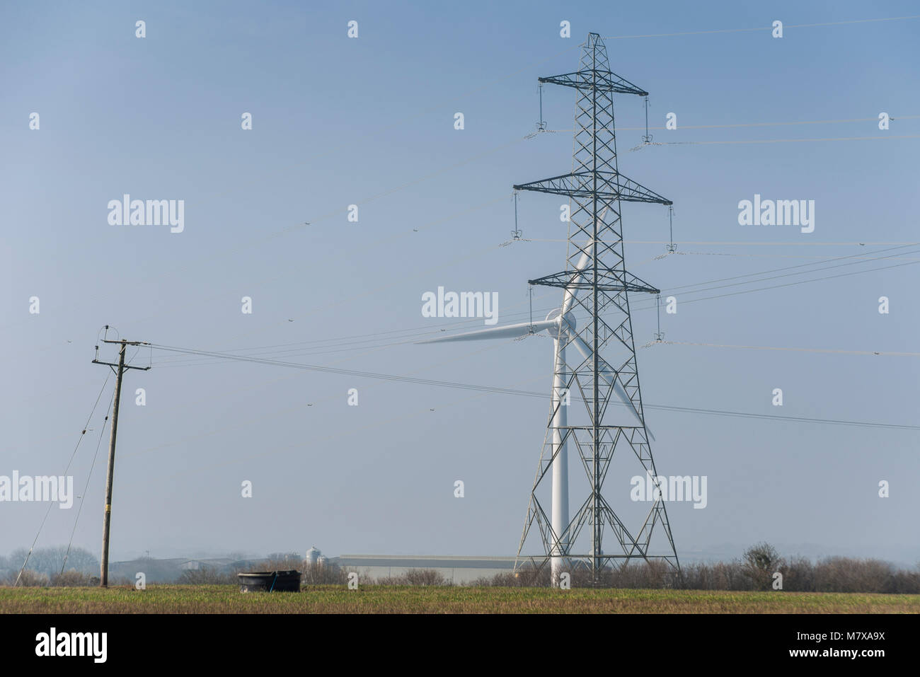 Wind turbine and electricity pylon in a rural area Stock Photo