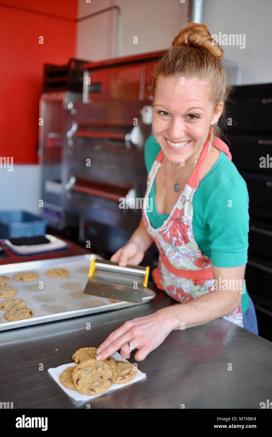 Woman baker working at her small commercial bakery kitchen in USA Stock