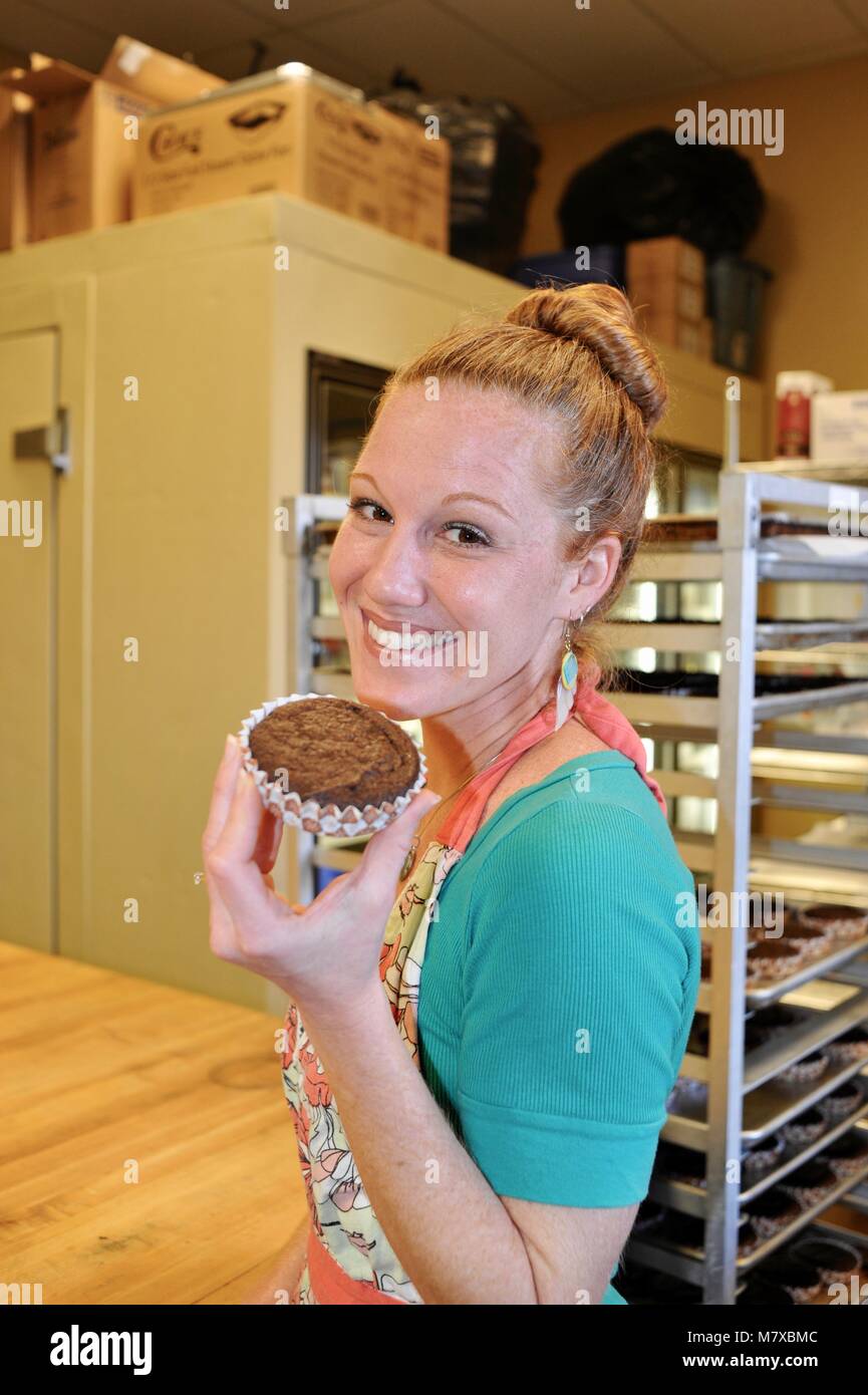 Woman baker working at her small commercial bakery kitchen in USA Stock