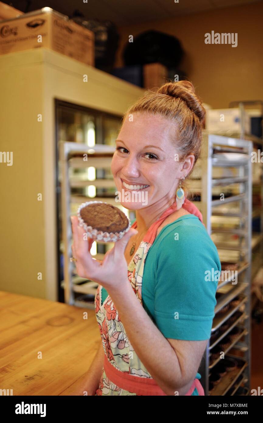Woman baker working at her small commercial bakery kitchen in USA Stock