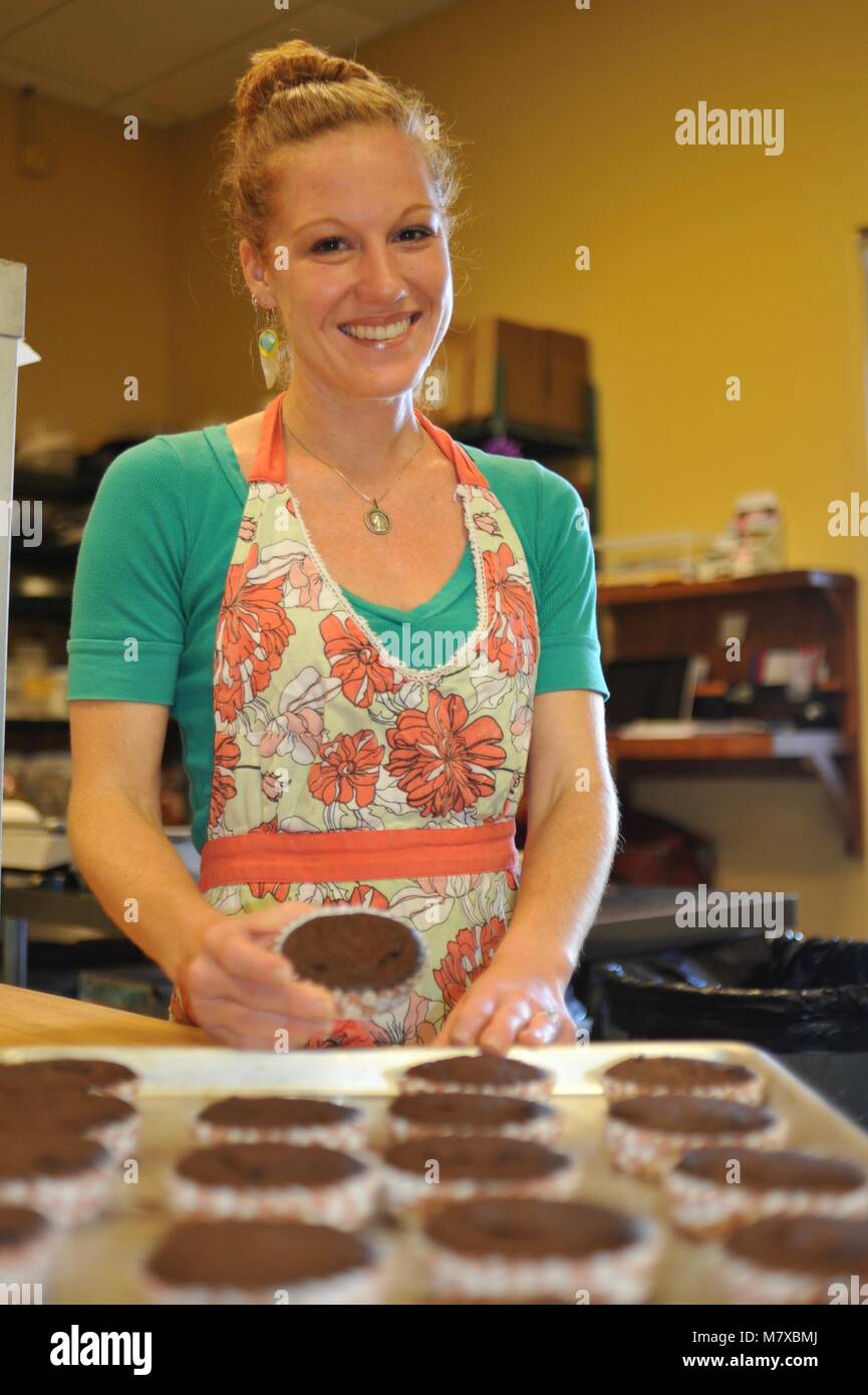 Woman baker working at her small commercial bakery kitchen in USA Stock