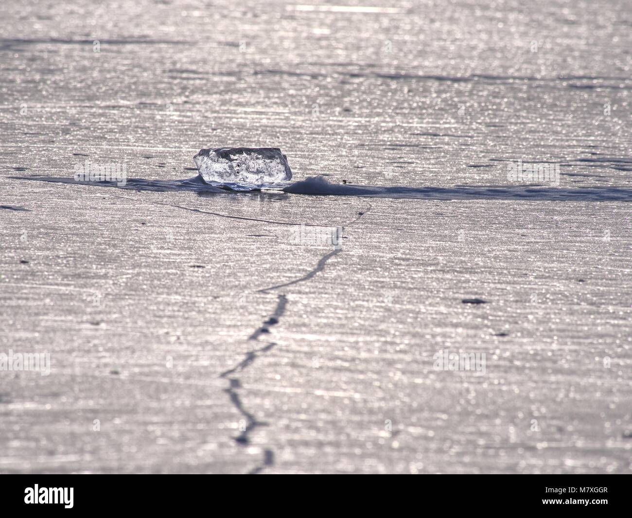 Shards of cracked ice jut out on the frozen lake. The light phenomenon occurs around a very specific time of year Stock Photo