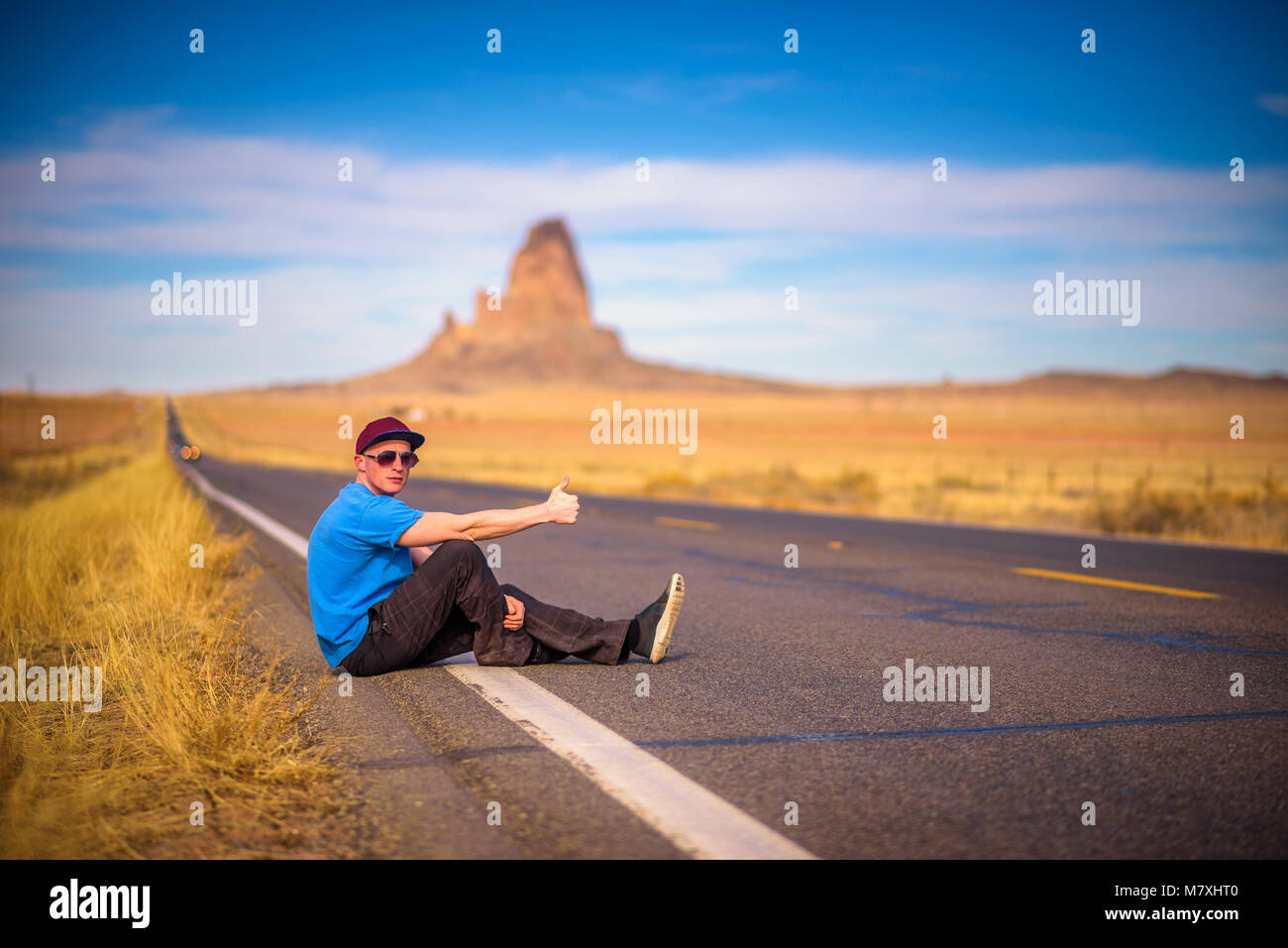 Tired hitch-hiker sitting on a road Stock Photo