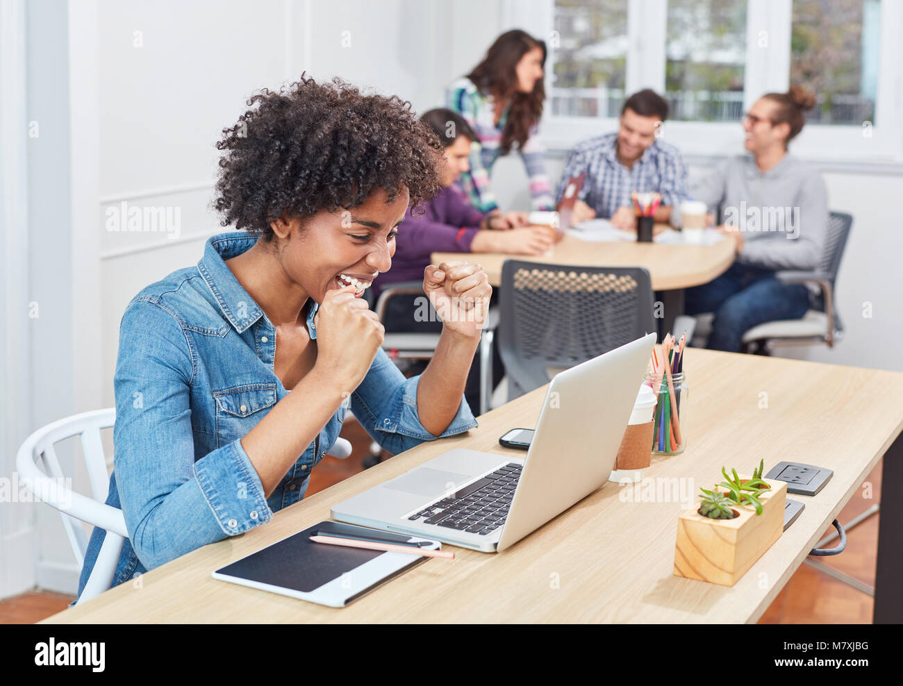 Start-up business woman in coworking office is happy about an idea on laptop Stock Photo