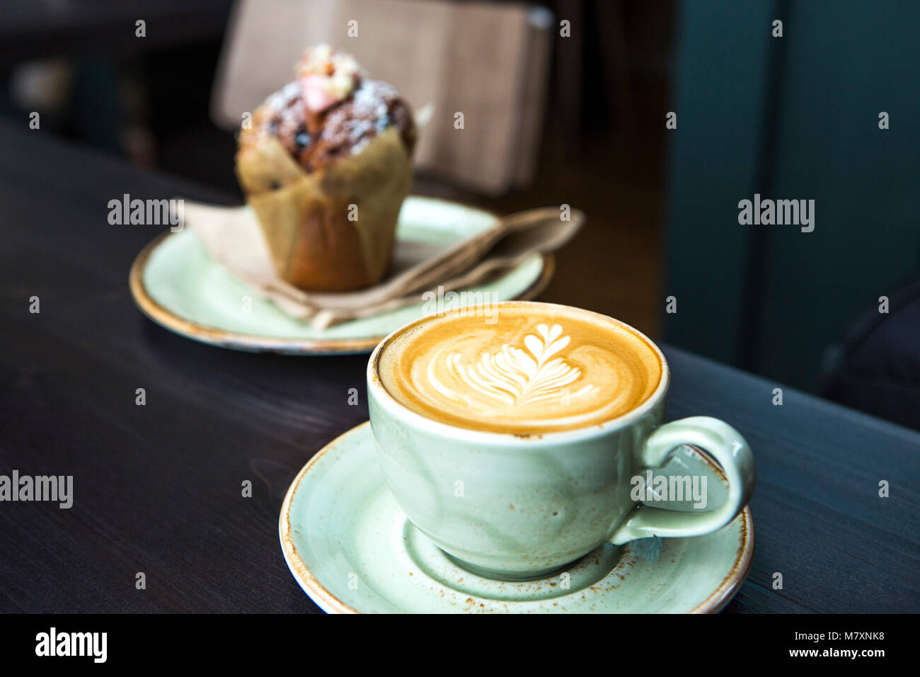 Cappuccino in green coffee cup and saucer with muffin. Stock Photo