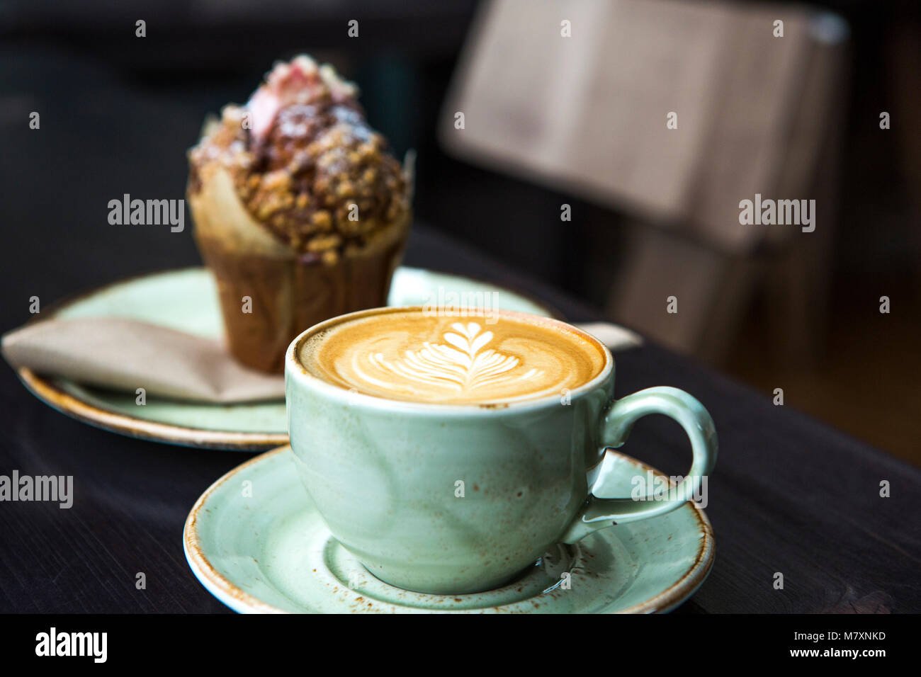 Cappuccino in green coffee cup and saucer with muffin. Stock Photo