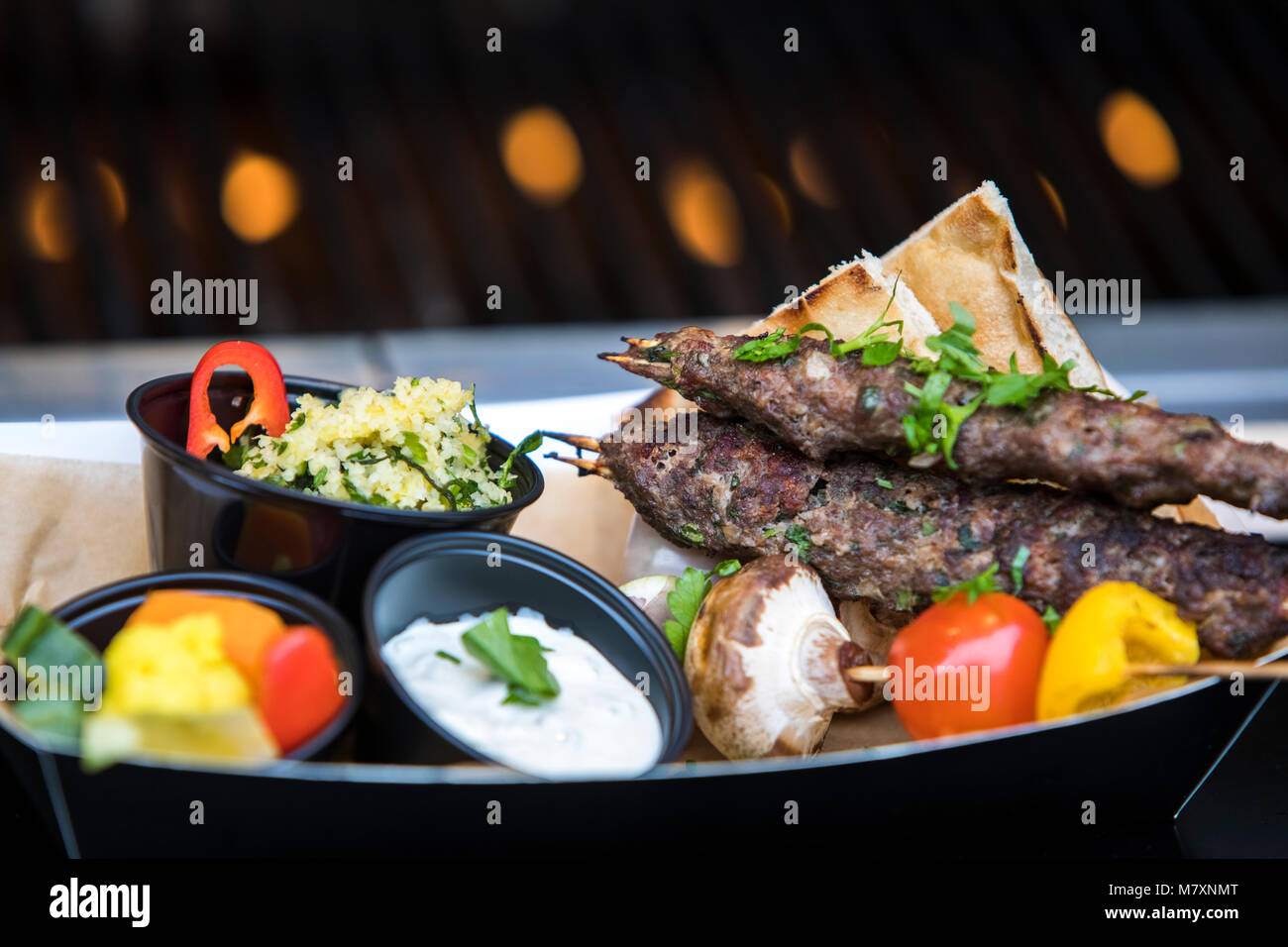 Middle Eastern street food.  Lamb kofta kebab, flatbreads, cous cous, yohurt, vegetable skewer. Stock Photo