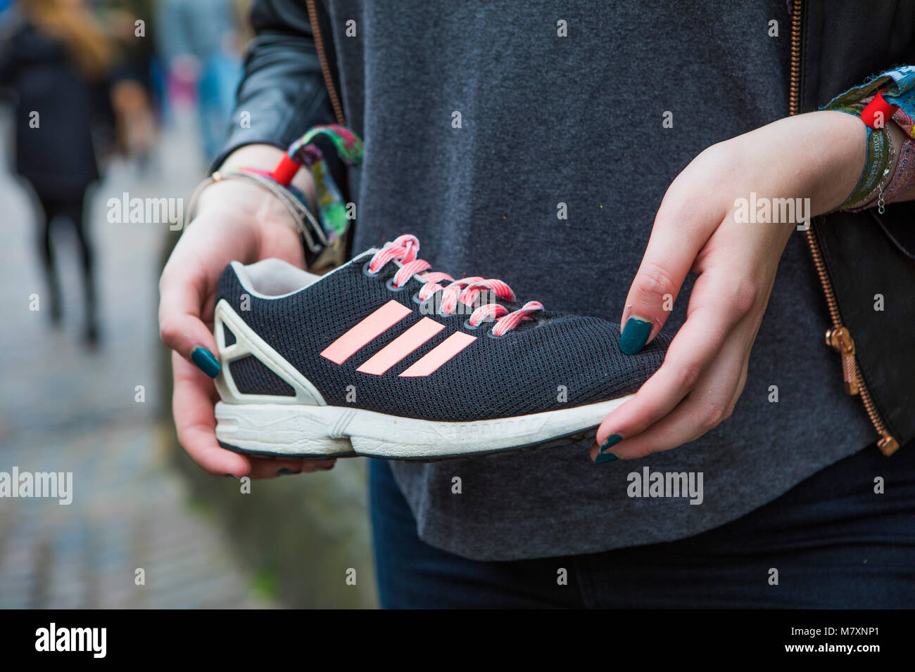 Cool vintage black Adidas trainer with pink stripes held by a woman. Stock Photo