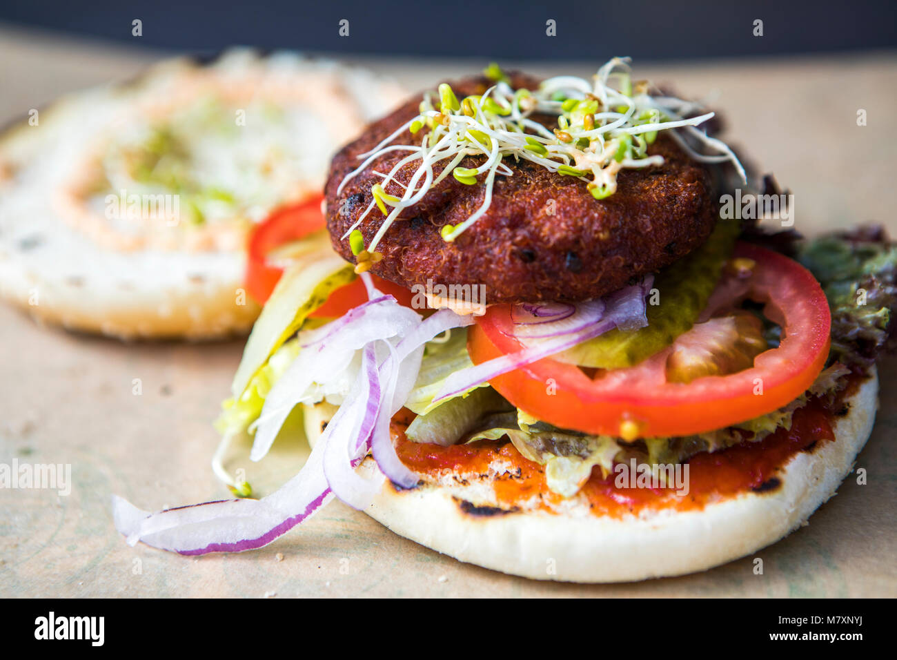 Quinoa burger, vegan street food with tomato and sprouting herbs. Stock Photo