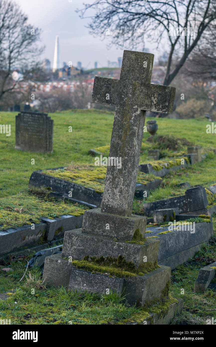 LONDON, UK – JAN 2018: Gravestones on Camberwell Cemetery in South London with skyscrapers of city in background Stock Photo