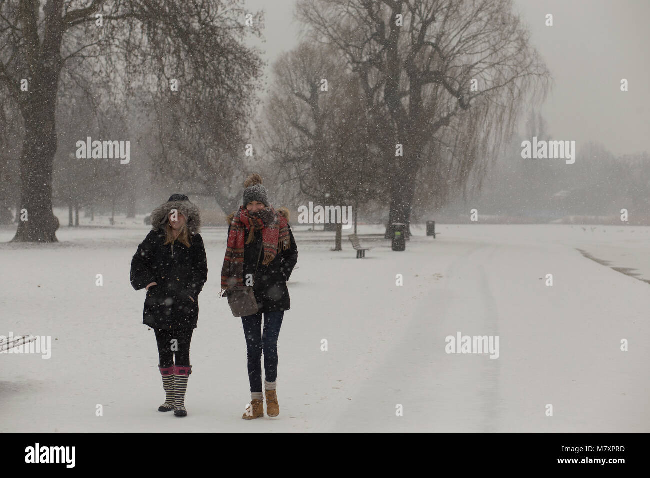 LONDON, UK: Two young women walking in white Regent's Park while it is snowing Stock Photo