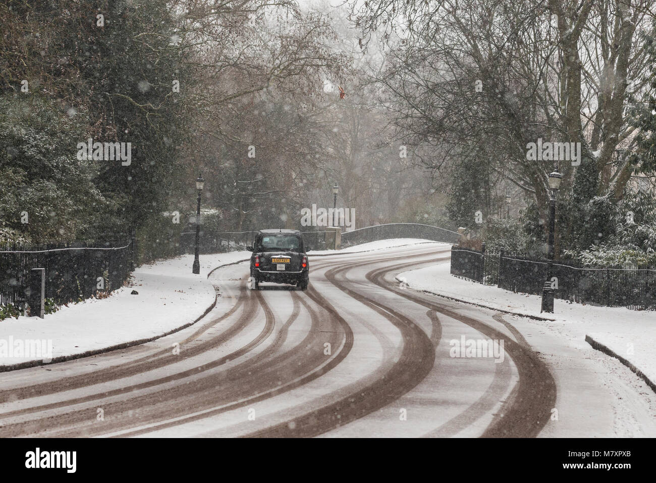 LONDON, UK – MAR 2018: Black cab driving on snow-covered road in north London Stock Photo