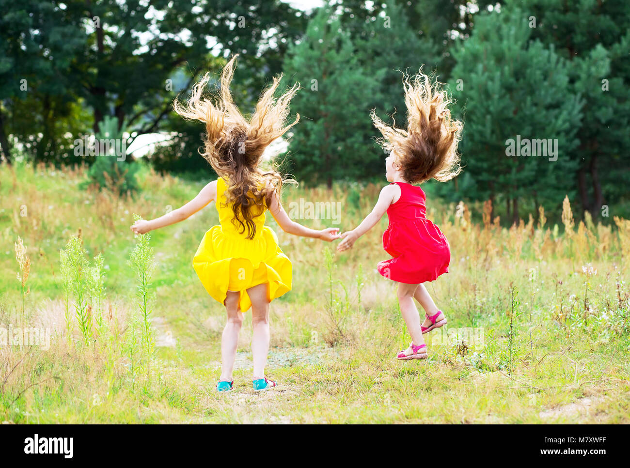 Two beautiful little girls  jumping and dancing at sunny summer day. Happy kids concept Stock Photo