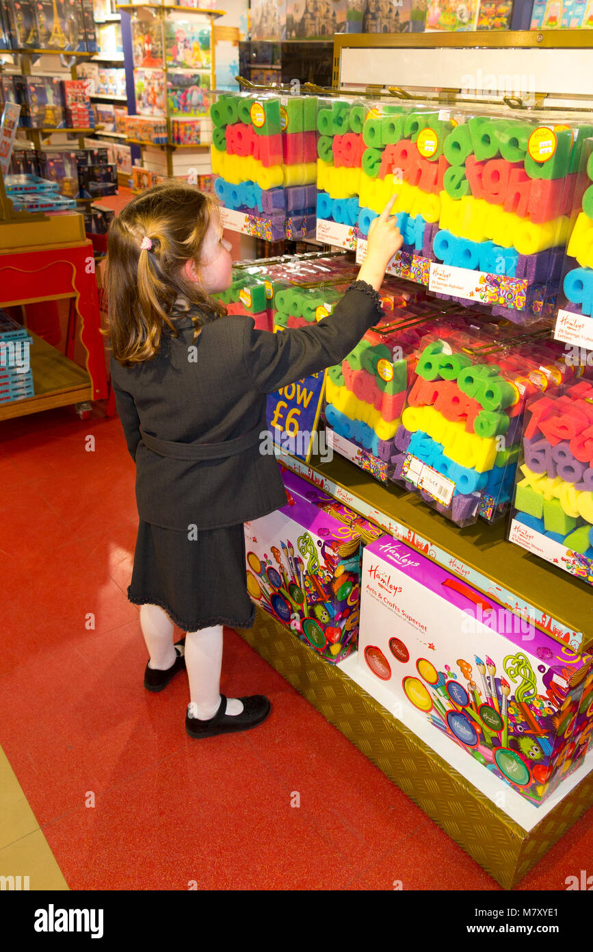 Young girl aged 6 year old / six years child / kids / children / kid looking and trying out the toys in a London toy shop. Regent Street, London, UK. Stock Photo