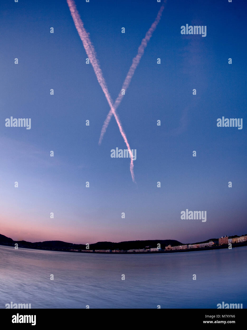 Aircraft vapour trails over Llandudno, North Wales coast at dawn Stock Photo