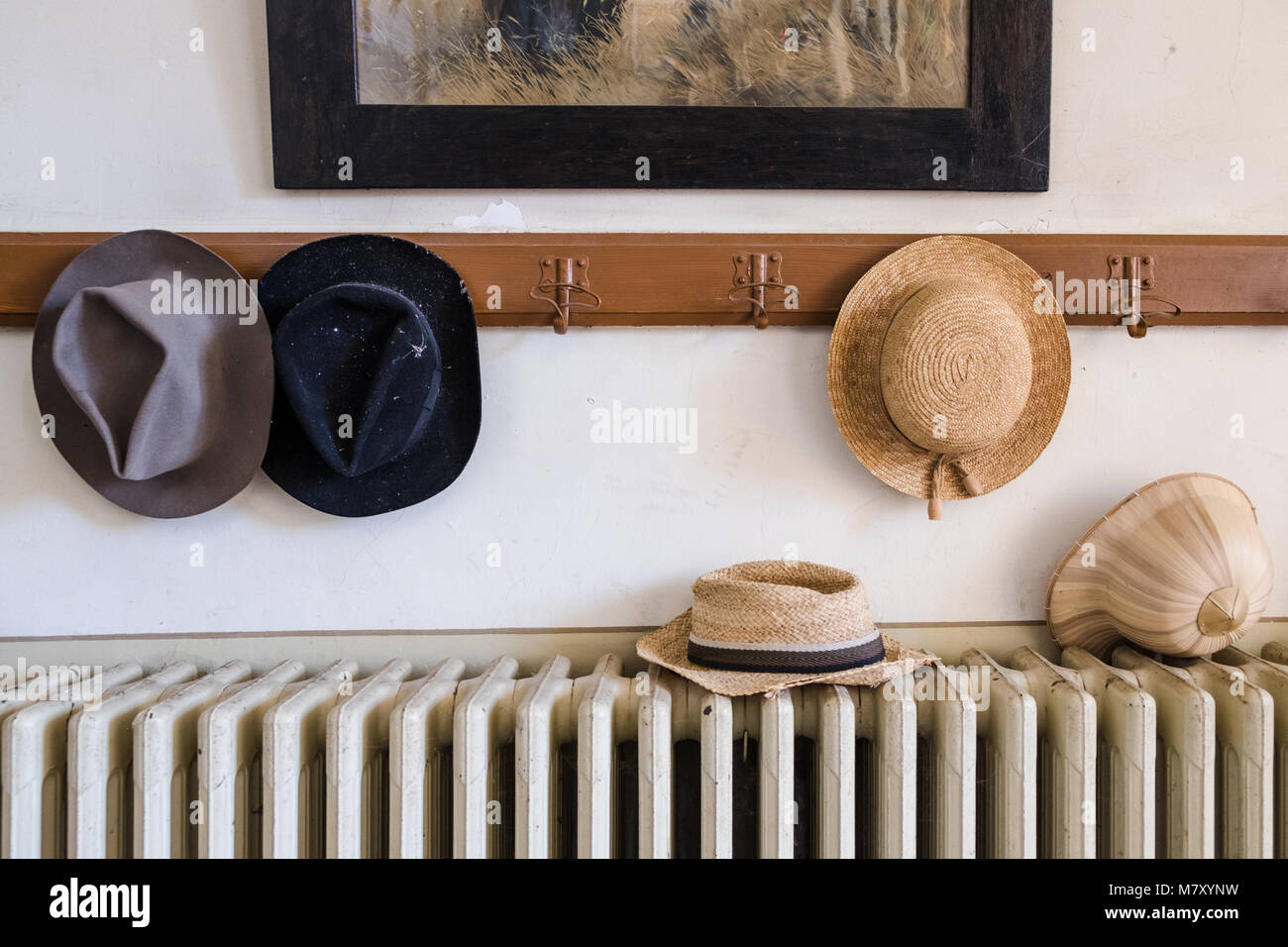 Wall hanger with various hats on it, radiator and old painting Stock Photo