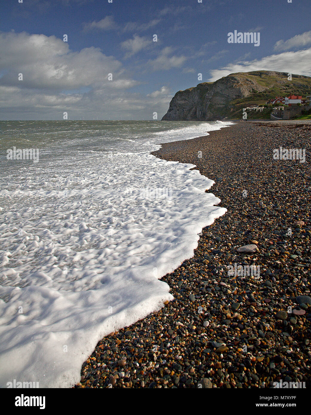 Foam and waves on the North Shore pebble beach, Llandudno, North Wales coast Stock Photo