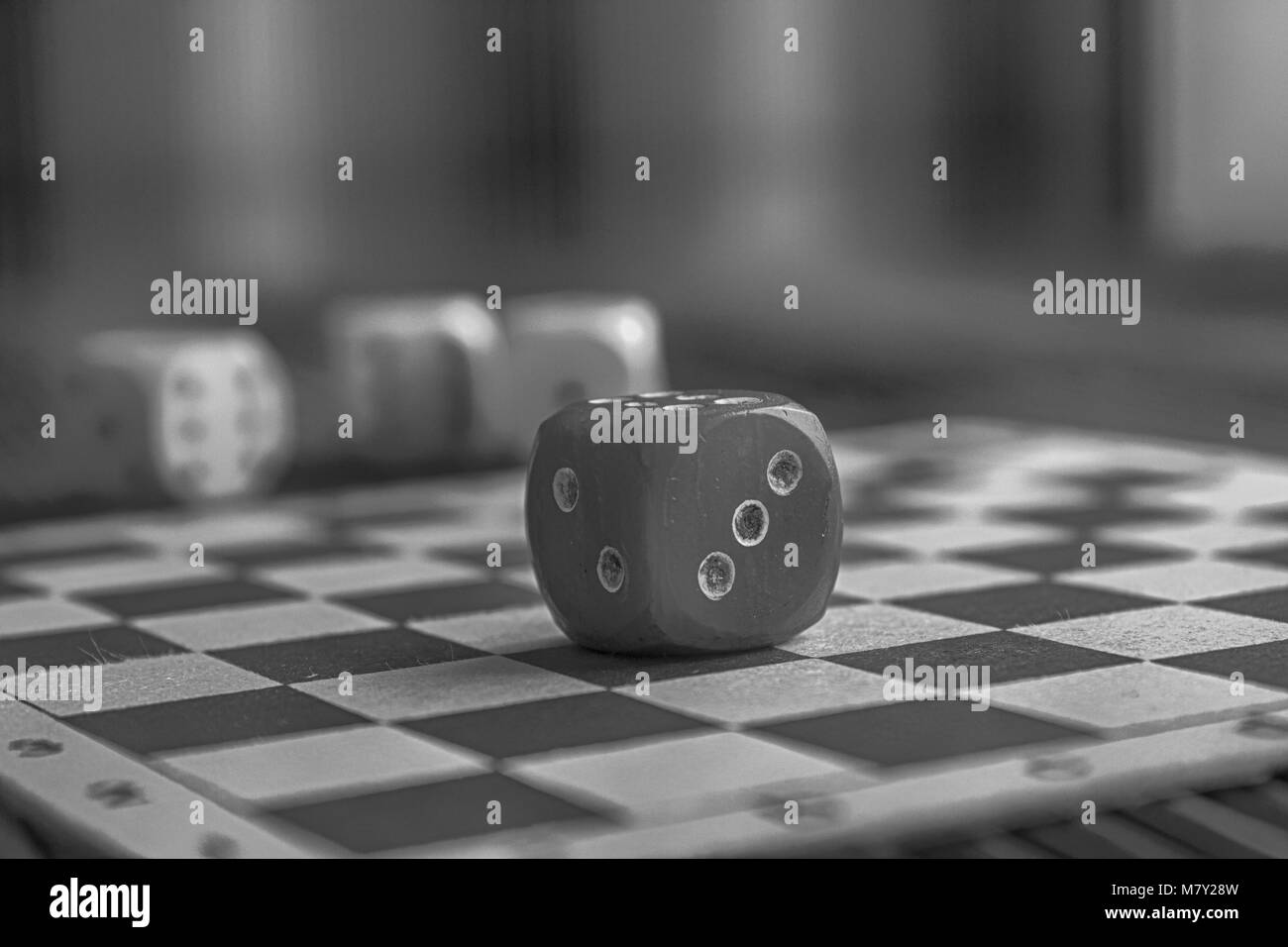 Monochrome plastic dice, one red dice on wooden board background. Six sides cube with black dots. Number 3, 2. Stock Photo