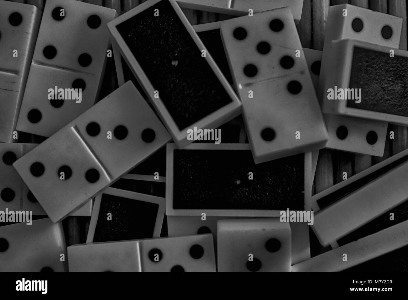 Monochrome Chaotic pile of domino pieces on the bamboo brown wooden table background Stock Photo